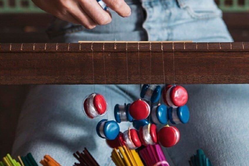 A person playing a stringed musical instrument with colorful beads. 5