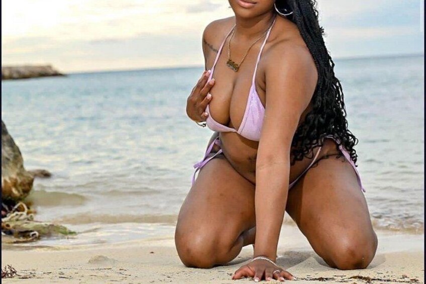 A person in a bikini on a sandy beach with the ocean in the background. 1
