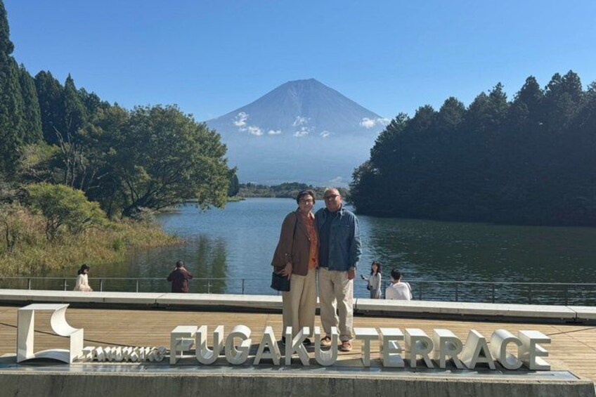 A lake with a mountain in the background, people standing on a platform with a sign that reads 'Fugakuterrage.' 3