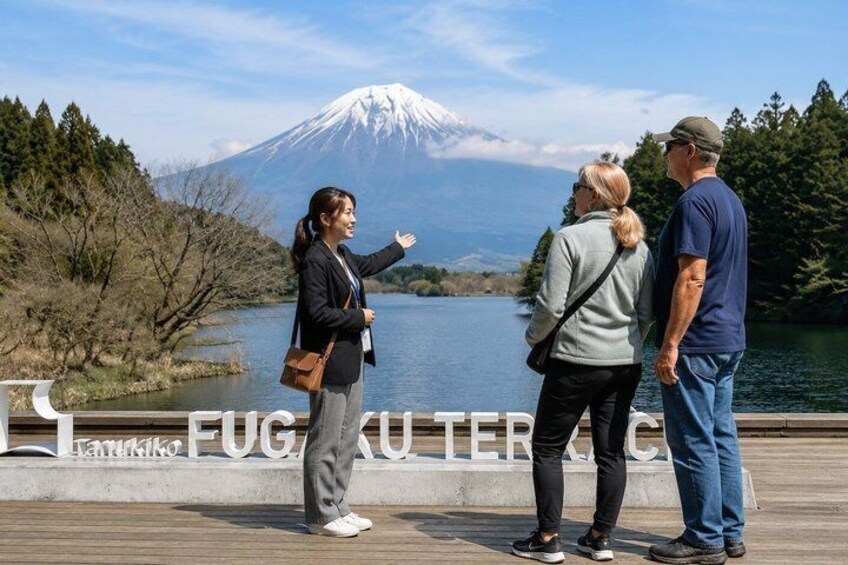 A group of people standing by a waterfront with a mountain in the background. 1