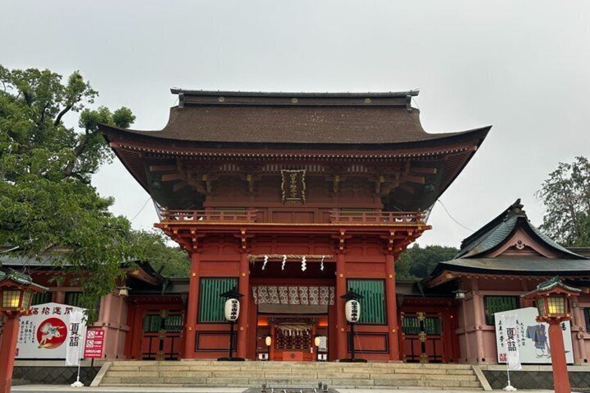 A traditional Japanese temple with a red gate, green doors, and a tiled roof. 4