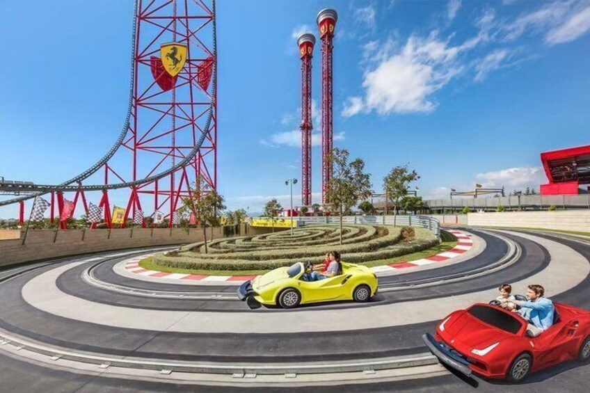 A racetrack with a Ferris wheel, red towers, and a red building. 5