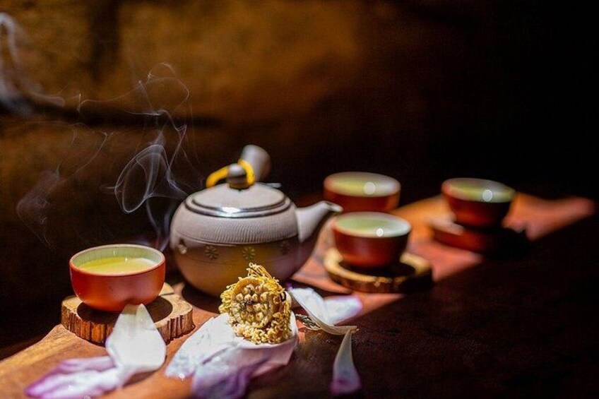 A teapot, cups, and loose tea leaves on a wooden surface. 4