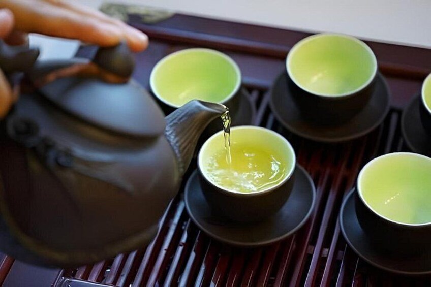 A teapot pouring tea into a cup. 3