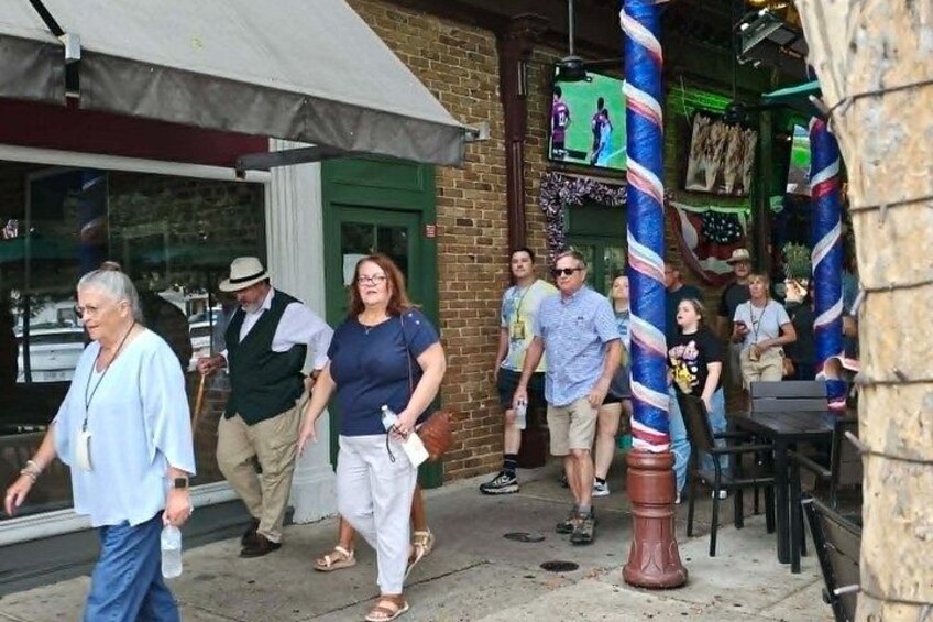 People walking outside a building with a brick facade and a green door. 5