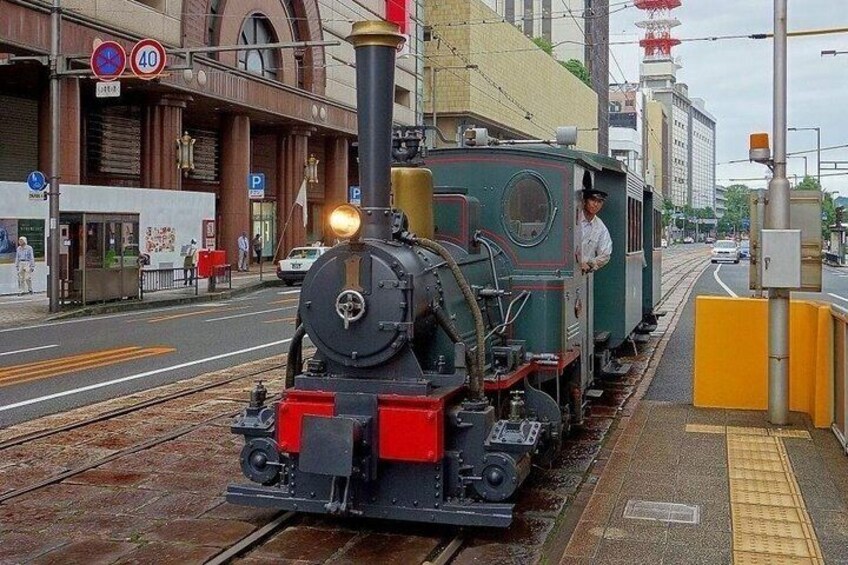 A steam locomotive on tracks with a station in the background. 2