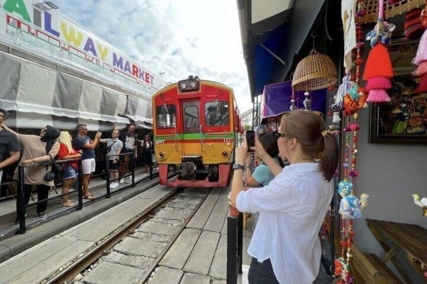 A train at a station with passengers and a market stall. 3