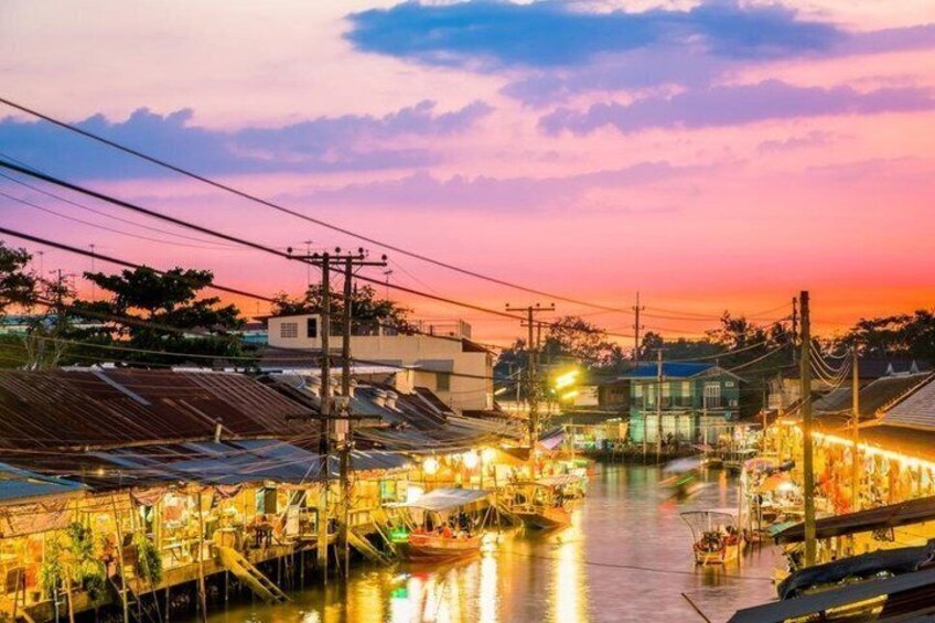 A riverside market at dusk with boats and illuminated stalls. 4