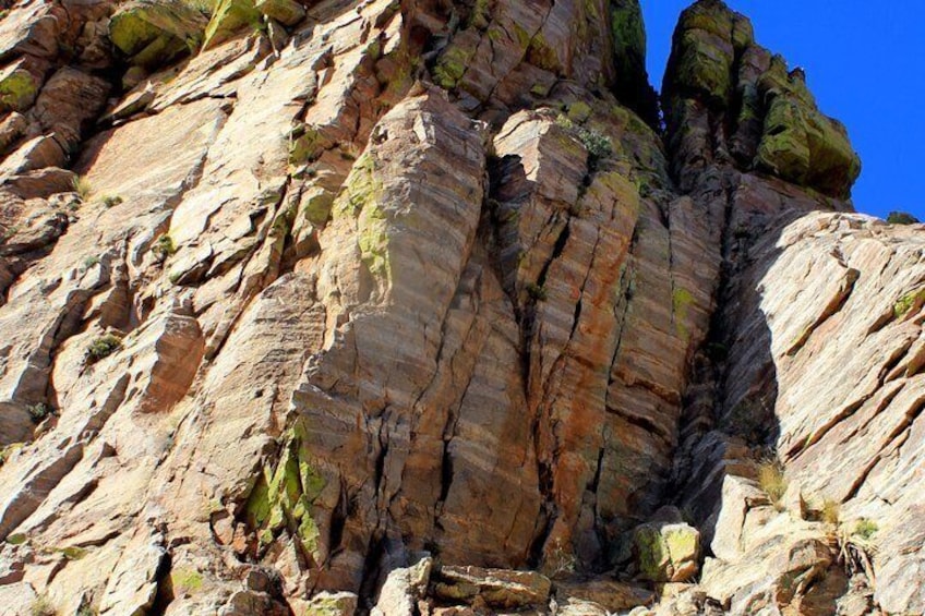 A rocky cliff with layered rock formations and some green vegetation. 4