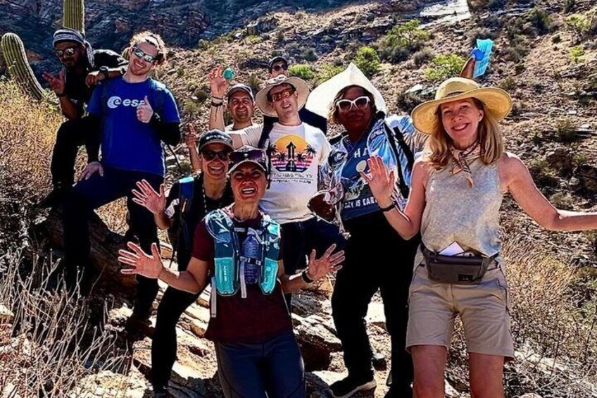 A group of people hiking on a trail with dry vegetation and rocky terrain. 2