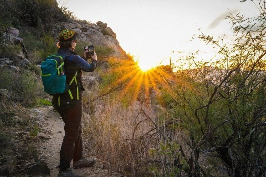 A person taking a photo with a smartphone on a hiking trail. 3