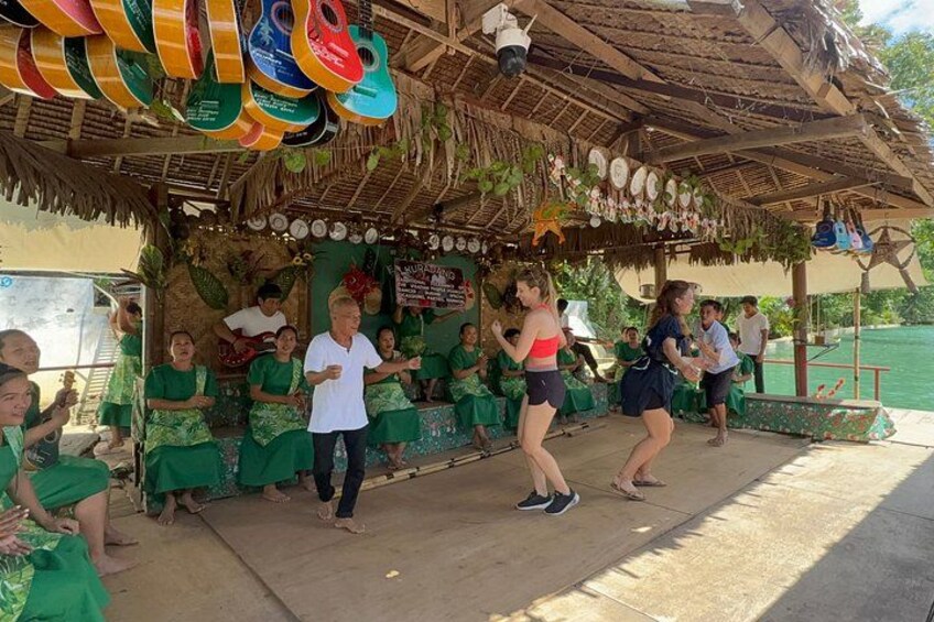 A group of people dancing under a thatched roof structure with decorative elements. 3
