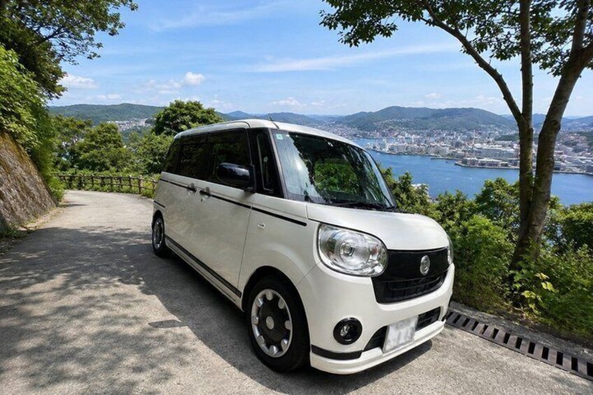 A white van parked on a road with a scenic view of a body of water and mountains in the background. 2