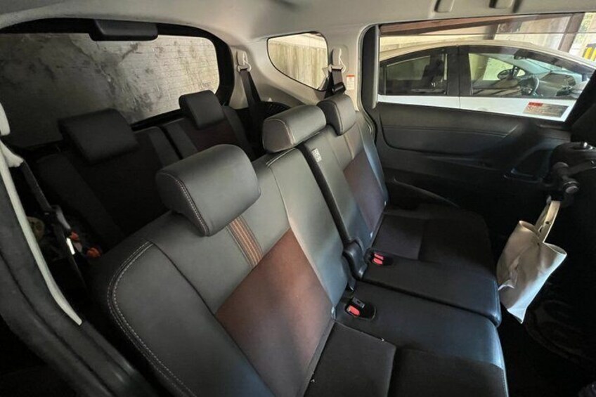 A car's interior with black and brown leather seats, a gear shift, and a rearview mirror. 2