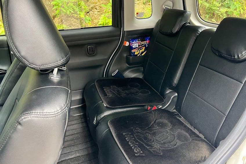 A car interior with black leather seats, a center console, and a rearview mirror. 4