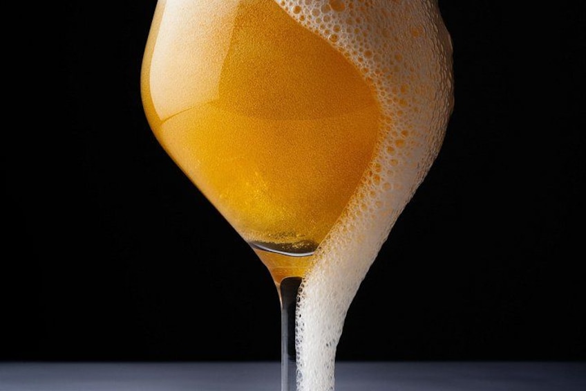 A glass of amber liquid with a foamy head, set against a dark background. 1