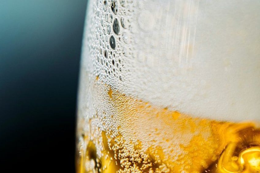 A close-up of a glass with a foamy head, likely containing a beverage. 5