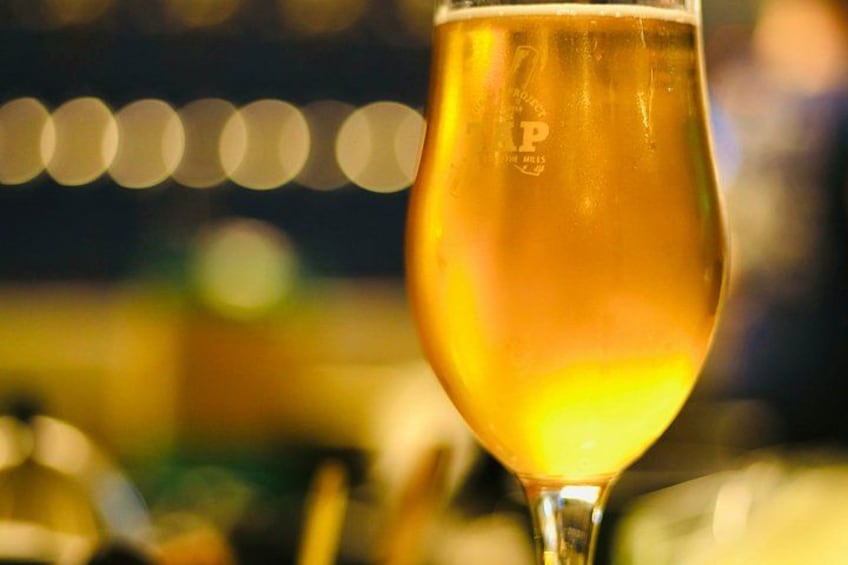 A close-up of a glass of beer with a blurred background of lights. 3