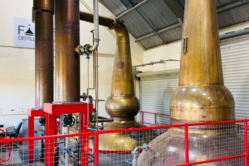 Industrial distillation equipment with large copper columns and a red safety railing. 2
