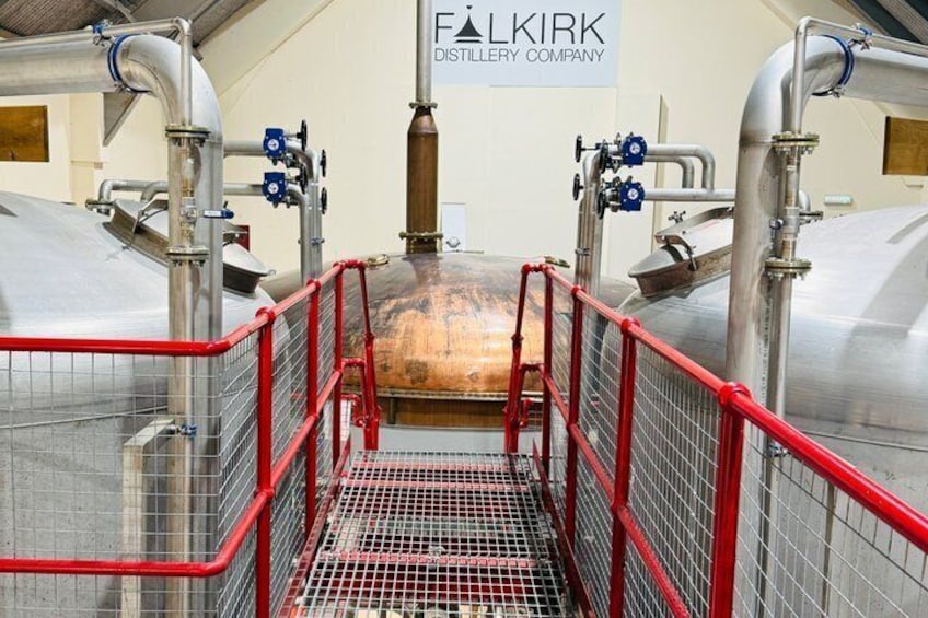 A distillery facility with stainless steel tanks, red safety railings, and a sign for Falkirk Distillery Company. 3