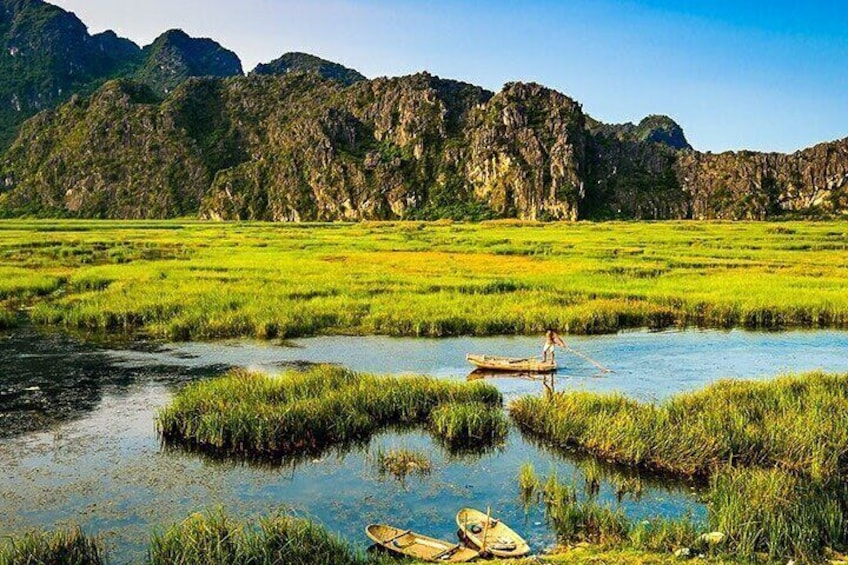 A river with boats, a person paddling, and a mountainous landscape in the background. 5