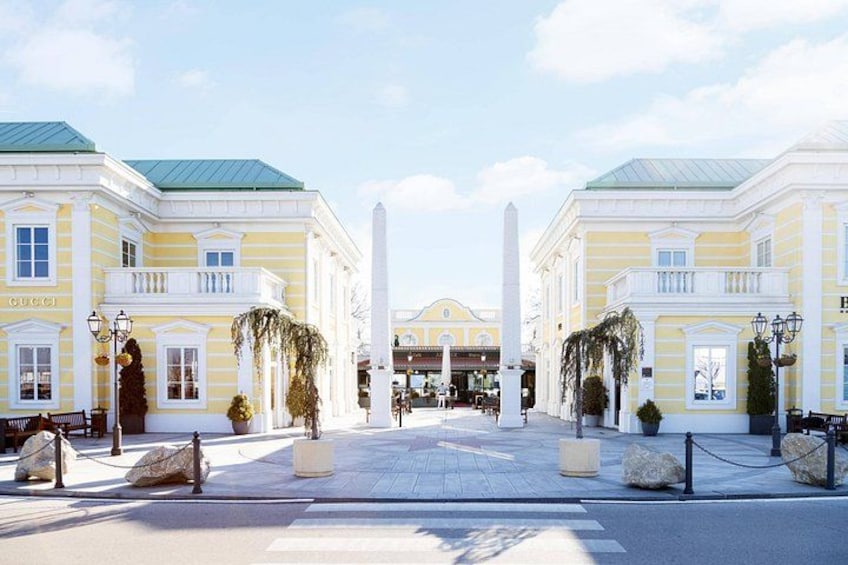 A historic building with a central monument, surrounded by symmetrical architecture and a paved plaza. 2