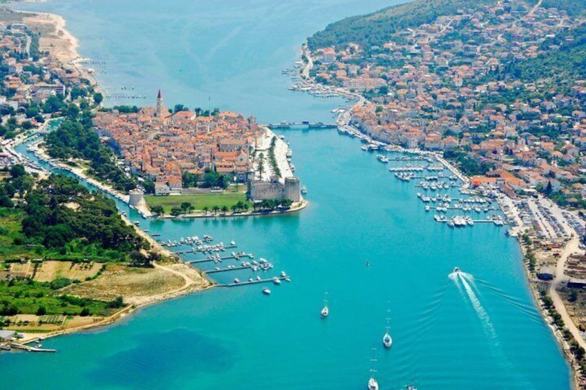 A coastal town with a prominent castle, a marina with boats, and a clear blue sea. 5