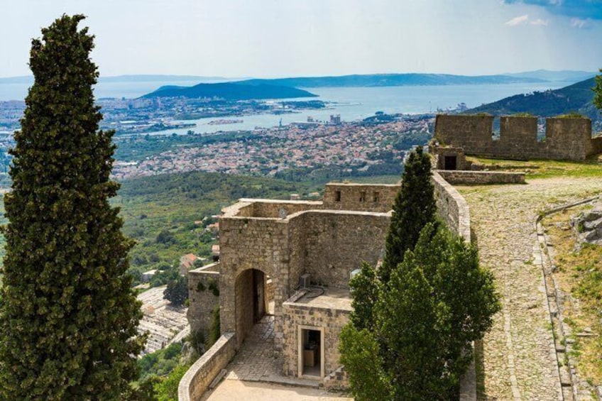 A stone fortress overlooking a city and sea. 3