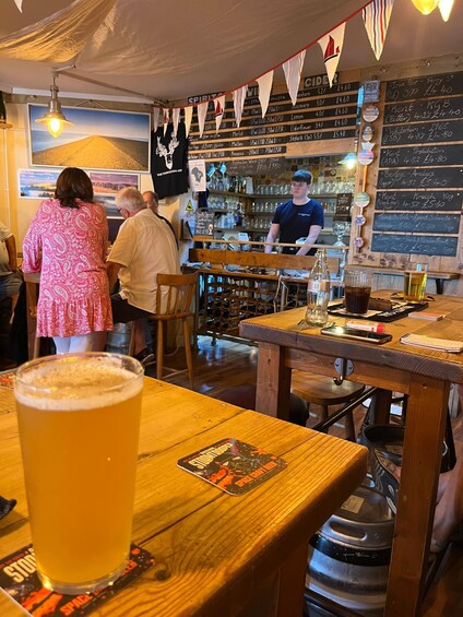 A bar with wooden tables, a large beer glass, and a chalkboard menu. 3