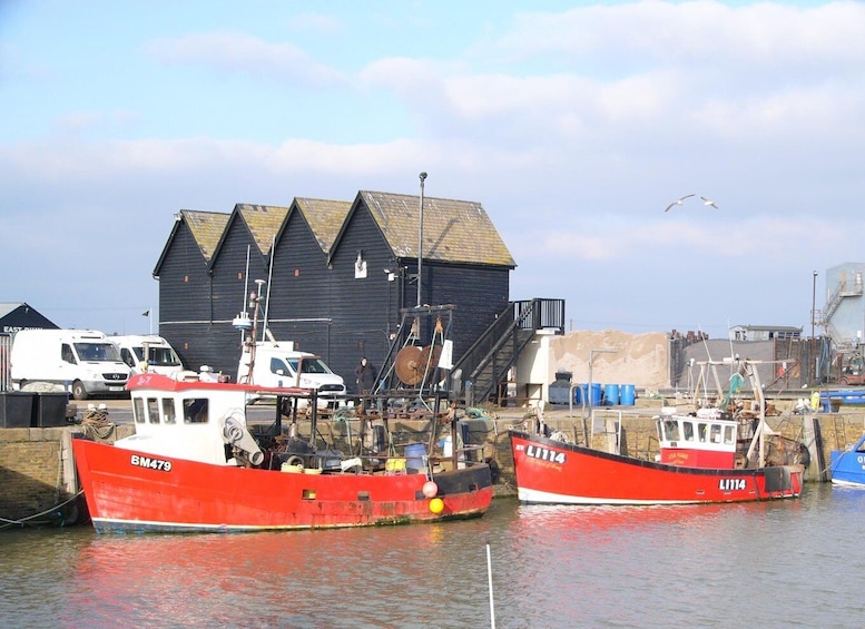 Two red fishing boats docked at a harbor with a large building in the background. 4