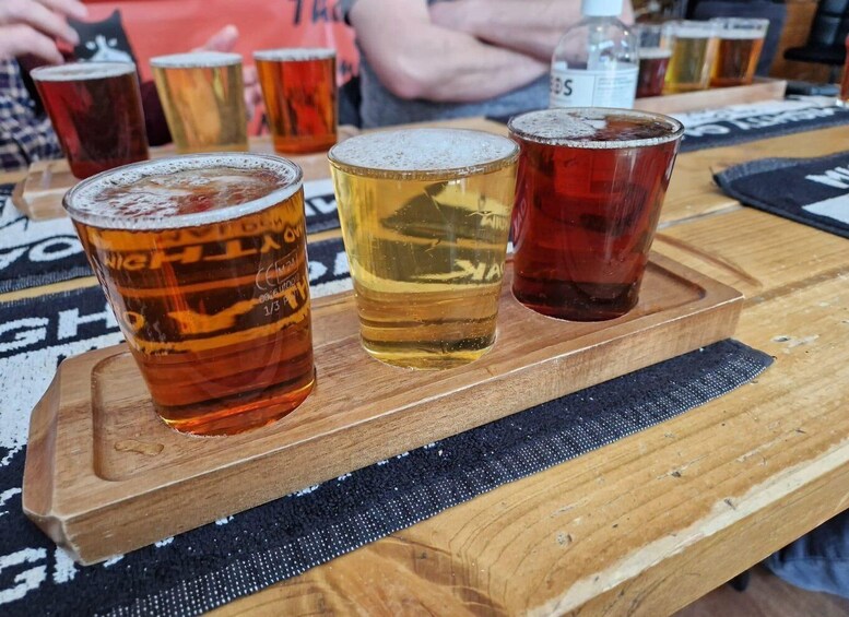 A wooden tray with three glasses of beer on a table. 1