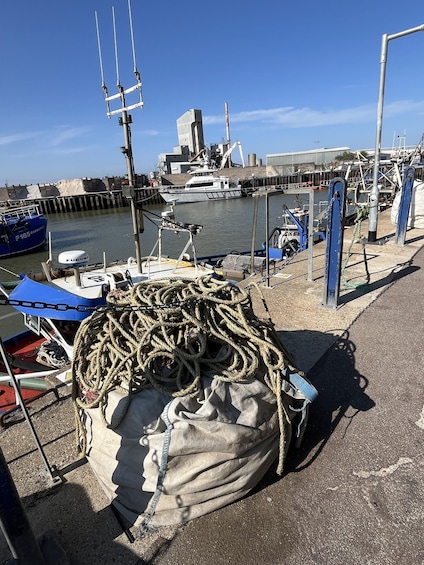 A harbor with boats docked, ropes, and a large bag of sand. 2
