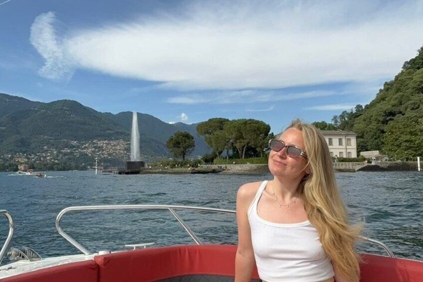 A person on a boat with a mountainous landscape and a fountain in the background. 4