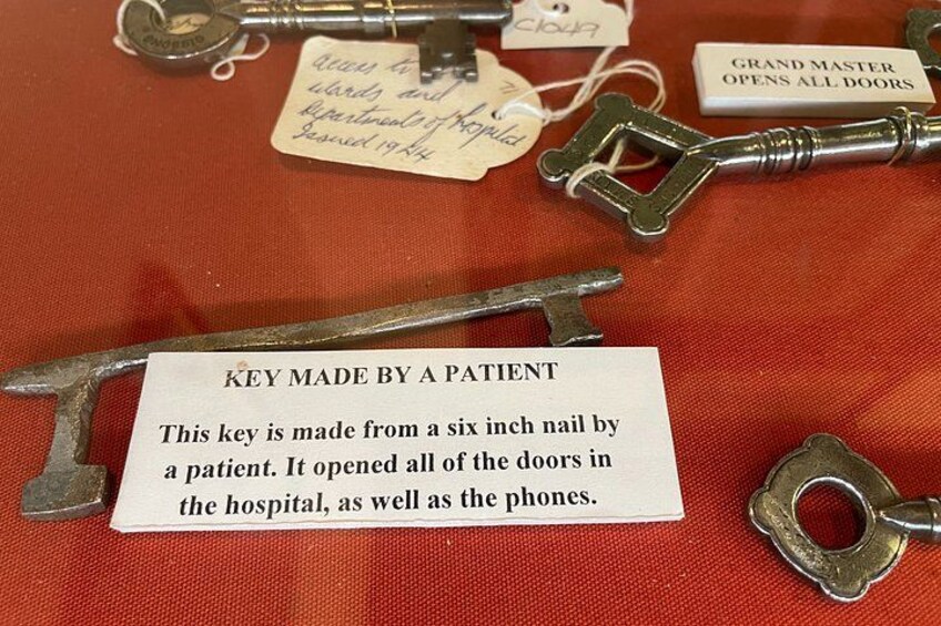 A collection of antique keys with a sign stating 'KEY MADE BY A PATIENT' and a note about a six-inch nail key. 4