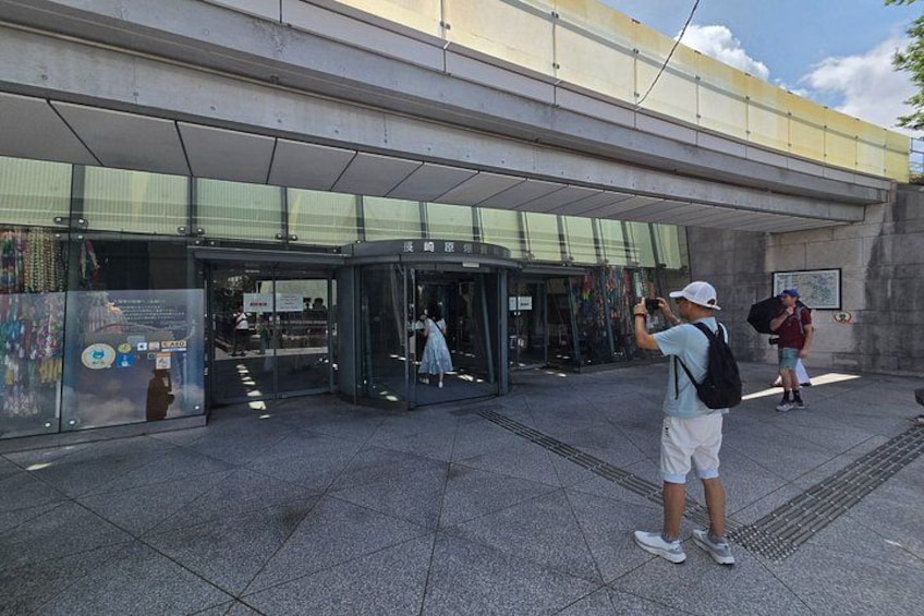 A modern building entrance with glass doors, a person taking a photo, and another person walking away. 4