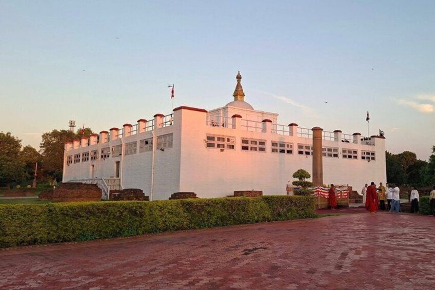 A white building with a dome and flagpole, surrounded by a paved area and greenery. 5