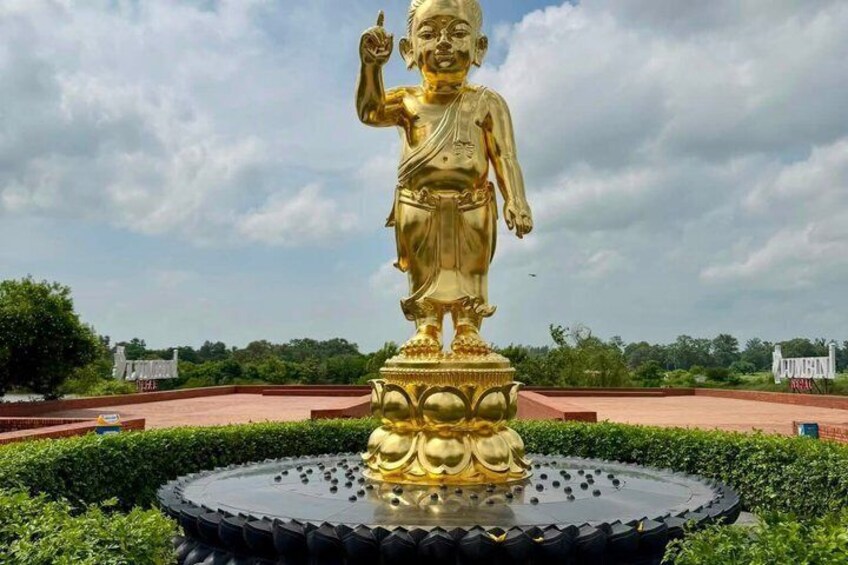 A golden statue on a circular platform with a fountain, surrounded by greenery. 3