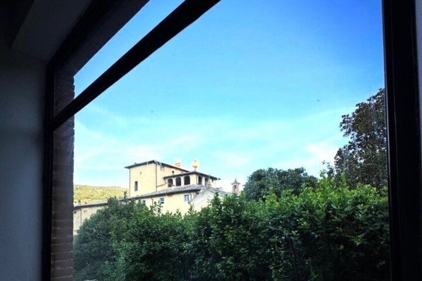 A building with a sloped roof and a bell tower, surrounded by dense green foliage. 3
