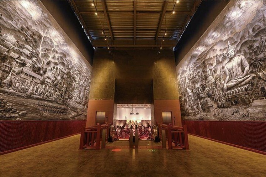 A large hall with intricate murals on the walls, a wooden floor, and a central aisle. 2