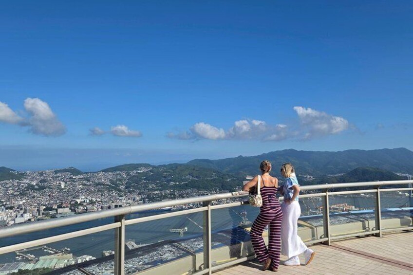 Two people overlooking a cityscape with a river and mountains in the background. 1