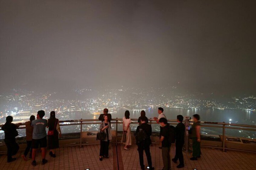 A group of people standing on a balcony overlooking a cityscape at night. 3