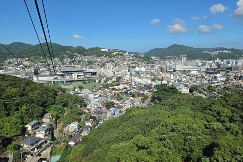 A cityscape with dense urban development, a large stadium, and surrounding green hills. 4