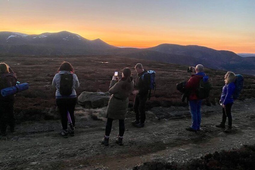 A group of people hiking on a mountain trail during sunset. 4