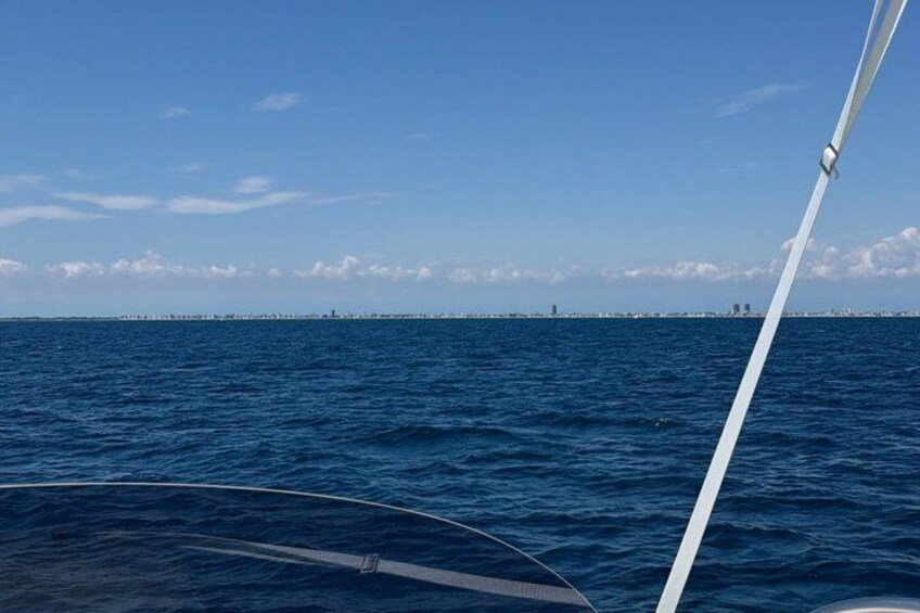 A body of water with a distant shoreline and a white sailboat. 1
