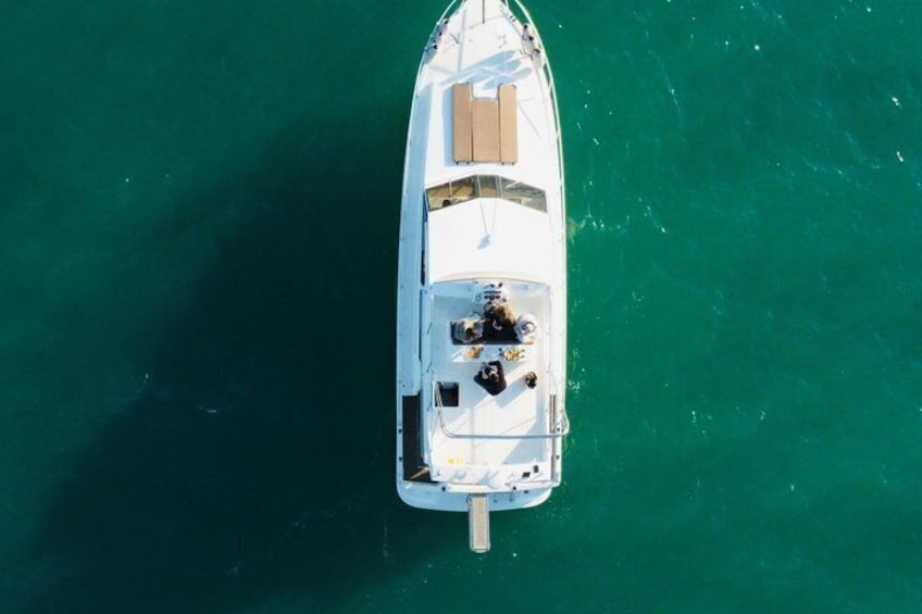 A white boat with a motor, a cabin, and a deck area, floating on greenish-blue water. 4