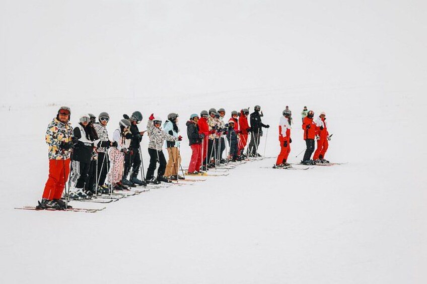 A group of skiers lined up on a snowy slope. 5