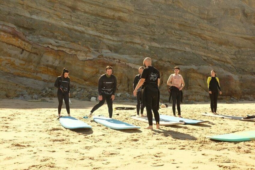 A group of people in wetsuits on a sandy beach with surfboards. 2