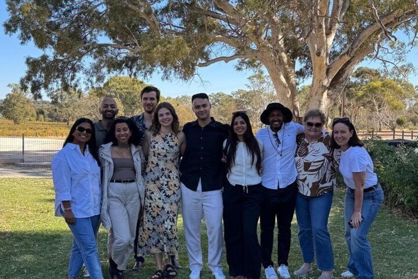 A group of people standing outdoors with a large tree in the background. 3
