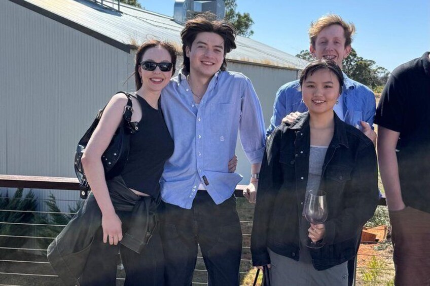 A group of people standing on a rooftop with a metal fence and a building in the background. 1