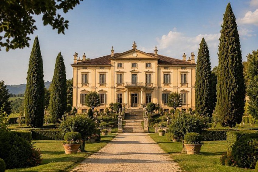 A large stately building with a symmetrical facade, surrounded by well-manicured gardens and tall cypress trees. 2